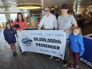 2023 50 Millionth Passengers are shown with a banner and the captain on board the Ferry