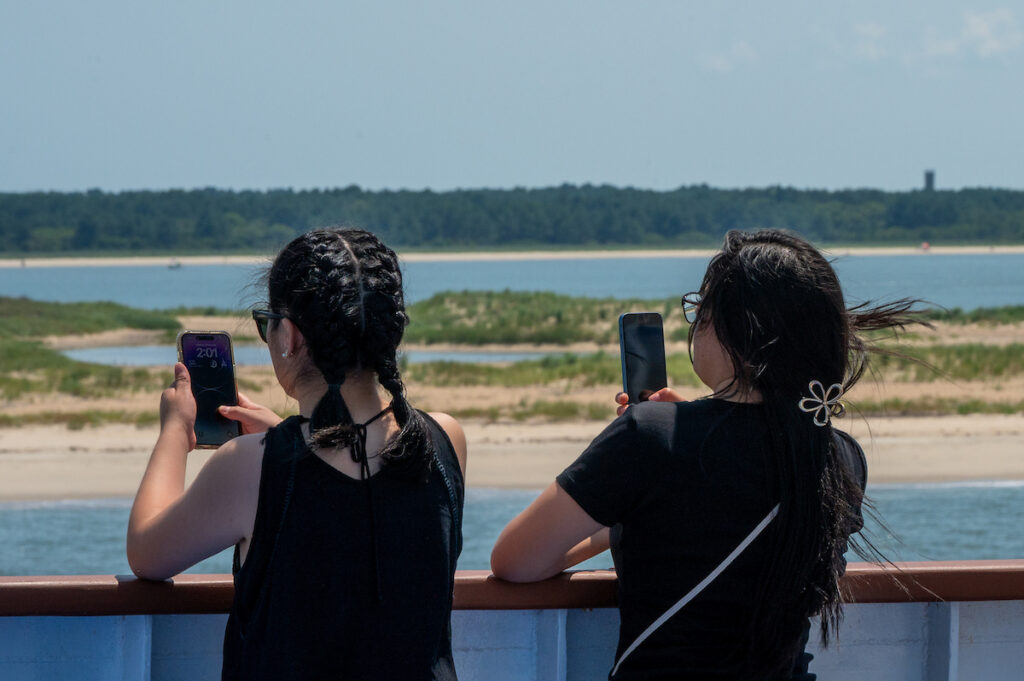 Passengers take photos of the lighthouse and the Harbor of Refuge from the deck of the Cape May - LEwes Ferry as it departs Lewes bound for Cape May.