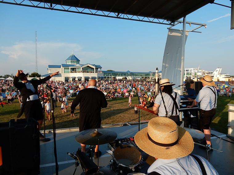 A packed lawn outside of Stowaways listens to the Amish Outlwas on stage at the Summer Concert Series