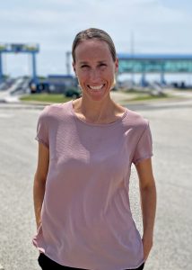 Photo of Jen Shivers smiling in a pink shirt in front of the Cape May Ferry Terminal to promote careers for women at the Ferry
